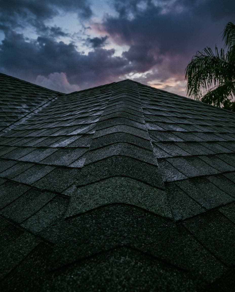 Telhas asfálticas novas e cumeeira em um telhado na Flórida ao entardecer, com nuvens de tempestade se dissipando